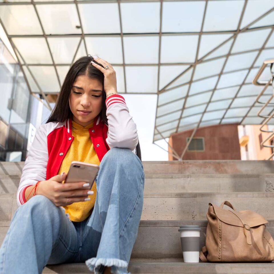 stressed person sitting on a stairway on their phone