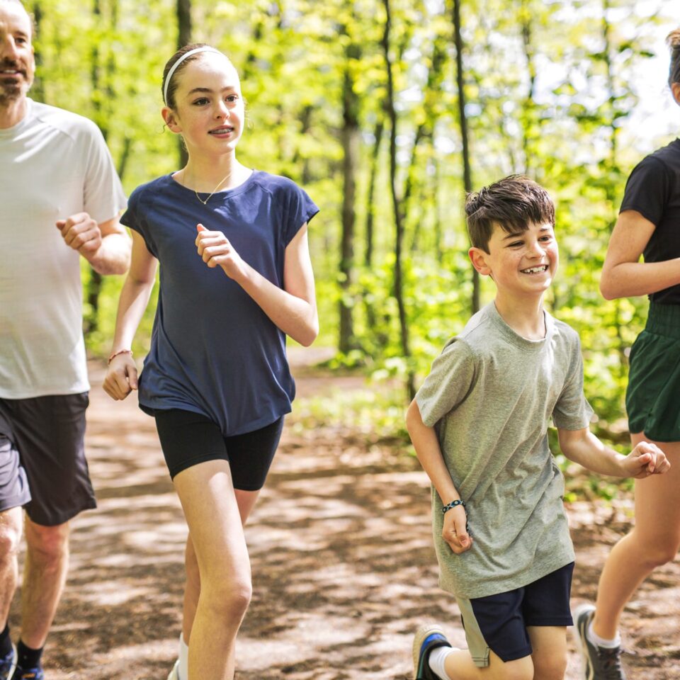 family of 4 jogging in the woods