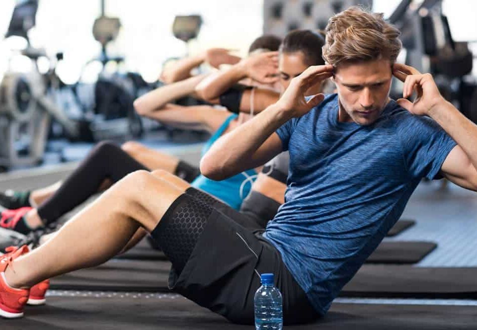 man exercising in a gym with company